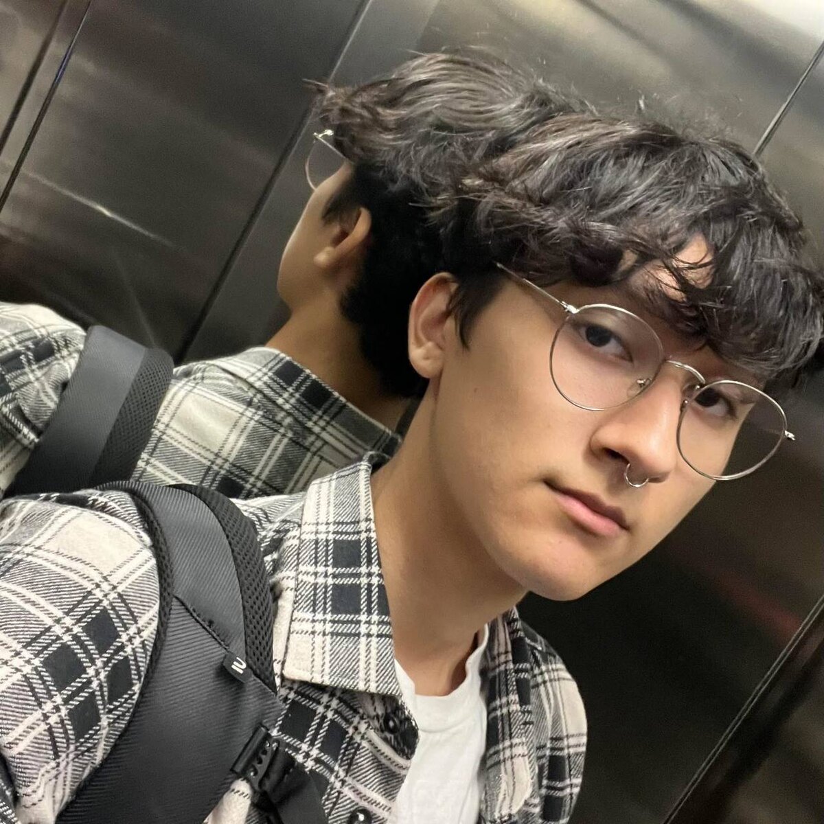 Renzo Ramos, ingeniero de inteligencia artificial (Junior AI Engineer) en Madrid, con gafas y camisa de cuadros